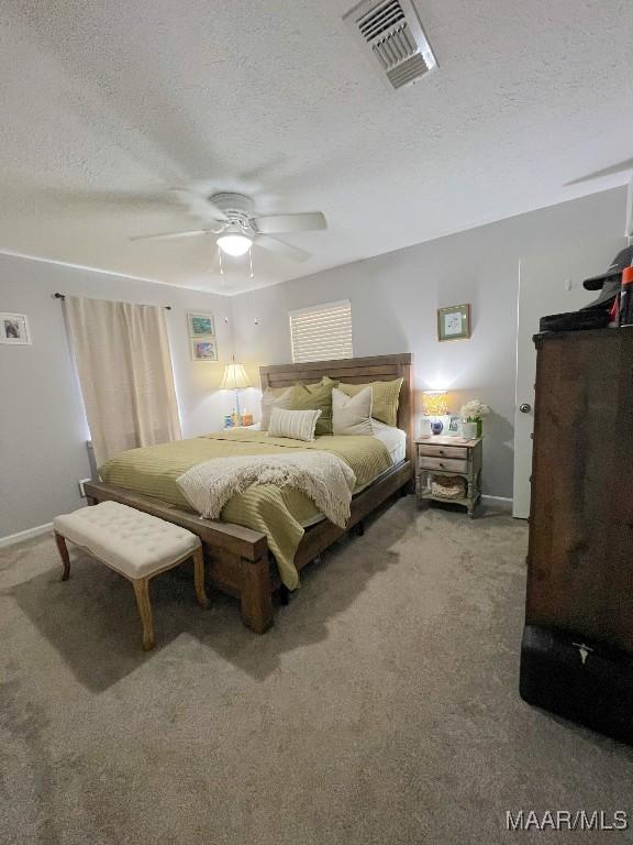 carpeted bedroom featuring ceiling fan, visible vents, and a textured ceiling