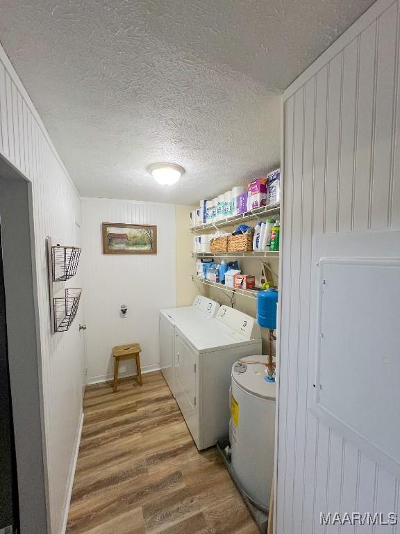 clothes washing area featuring a textured ceiling, laundry area, separate washer and dryer, wood finished floors, and baseboards