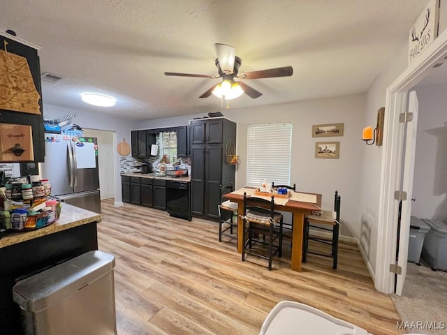 kitchen with light countertops, visible vents, light wood-style flooring, freestanding refrigerator, and dark cabinets