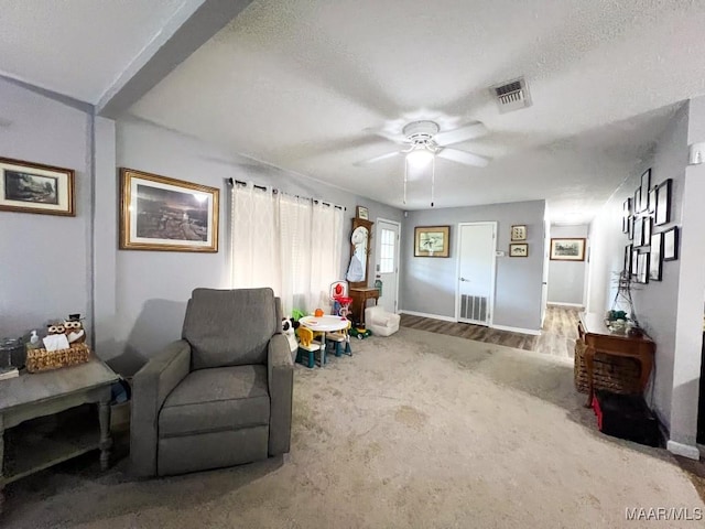 living area featuring baseboards, ceiling fan, visible vents, and wood finished floors