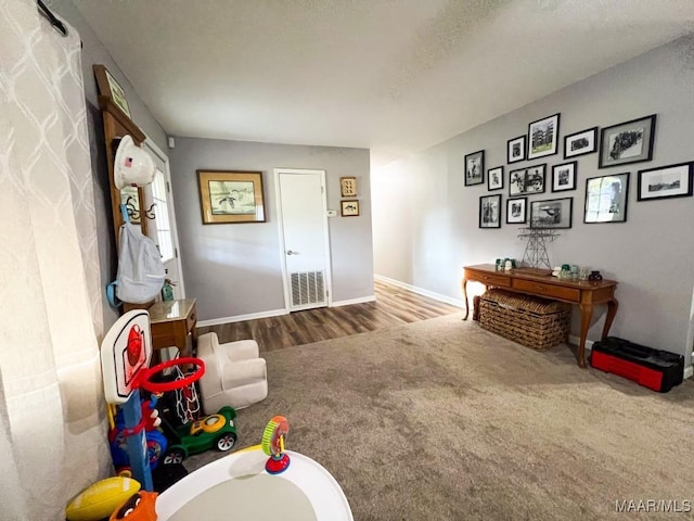 playroom featuring carpet floors, baseboards, and wood finished floors