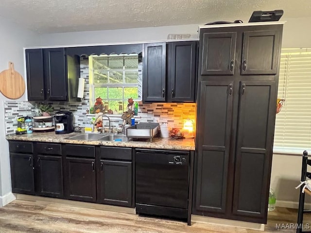 bar featuring light wood-style floors, black dishwasher, tasteful backsplash, and a sink