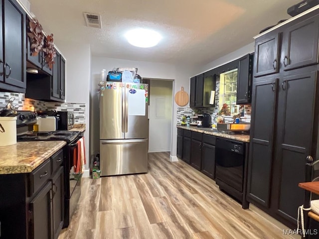 kitchen featuring light wood-style floors, visible vents, backsplash, and black appliances