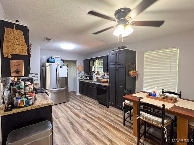 kitchen with light wood finished floors, visible vents, freestanding refrigerator, dark cabinets, and dishwasher