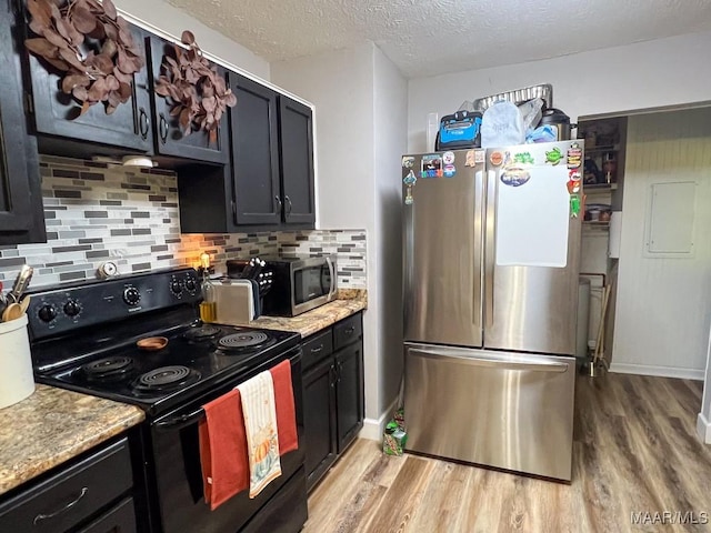 kitchen featuring tasteful backsplash, light wood-style flooring, light stone countertops, stainless steel appliances, and a textured ceiling