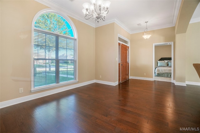 spare room with crown molding, dark hardwood / wood-style floors, and a notable chandelier