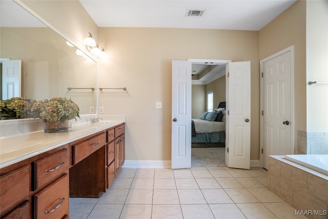 bathroom featuring tiled bath, vanity, and tile patterned flooring