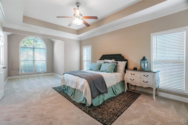 bedroom with light carpet, ceiling fan, a raised ceiling, and ornamental molding