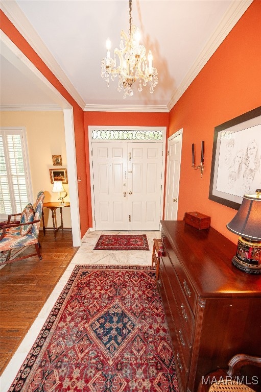 entryway featuring ornamental molding, a notable chandelier, and hardwood / wood-style flooring