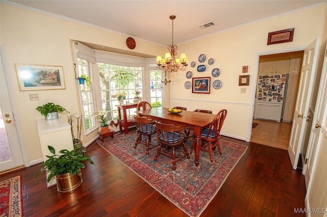 dining space featuring ornamental molding, dark wood-type flooring, and a chandelier