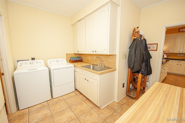 laundry area with cabinets, crown molding, washer and dryer, and sink