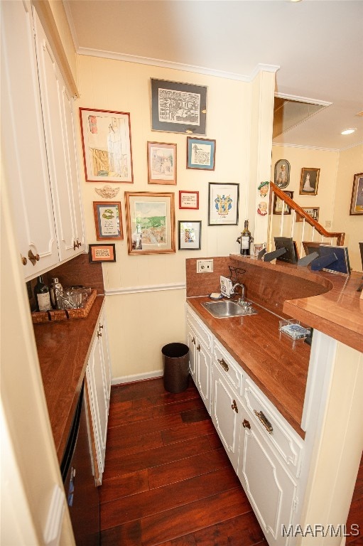 bar featuring ornamental molding, sink, dark hardwood / wood-style flooring, and white cabinetry