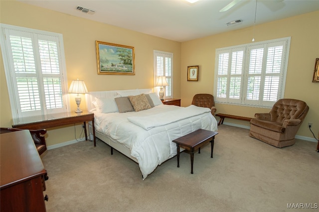 bedroom with light carpet, multiple windows, and ceiling fan