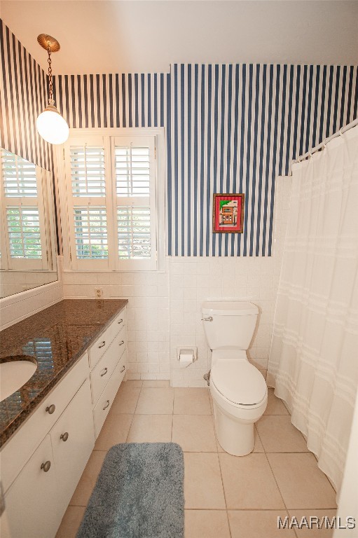 bathroom featuring a healthy amount of sunlight, tile walls, vanity, and toilet