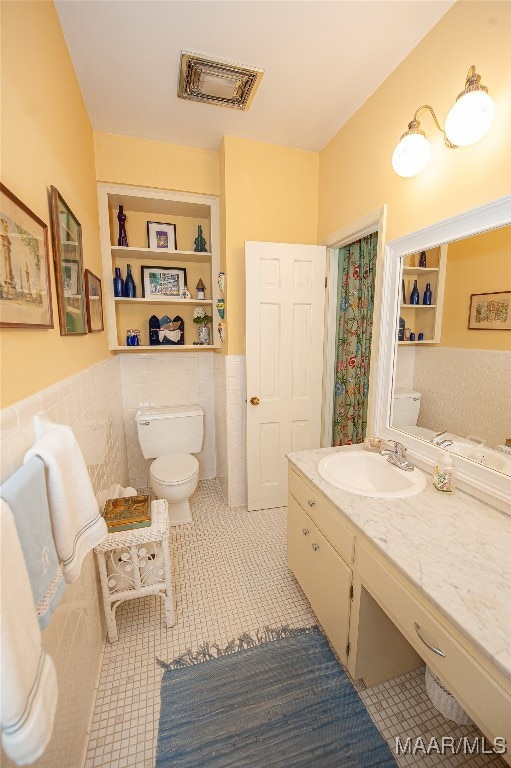 bathroom featuring tile walls, vanity, toilet, and tile patterned floors