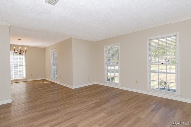 unfurnished room featuring crown molding, light hardwood / wood-style floors, a textured ceiling, and an inviting chandelier