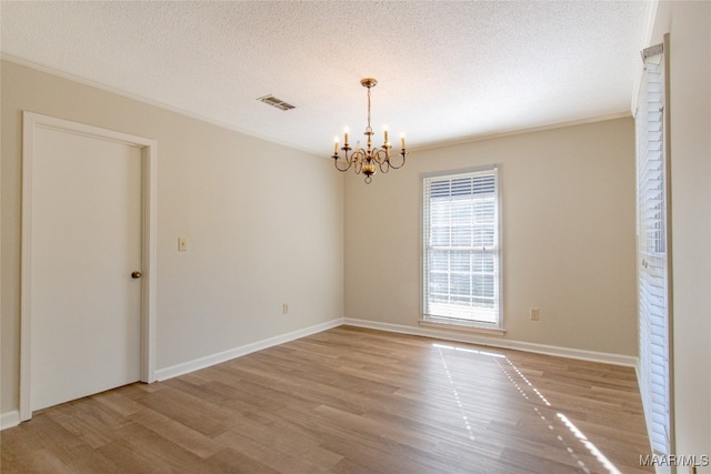 empty room featuring a chandelier, a textured ceiling, and light hardwood / wood-style flooring