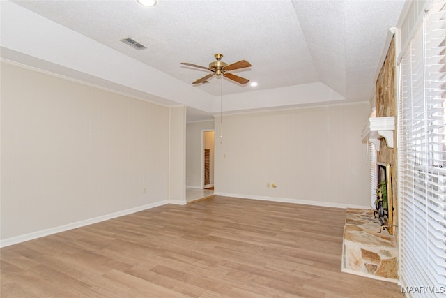 unfurnished living room featuring a textured ceiling, light hardwood / wood-style floors, a raised ceiling, and ceiling fan