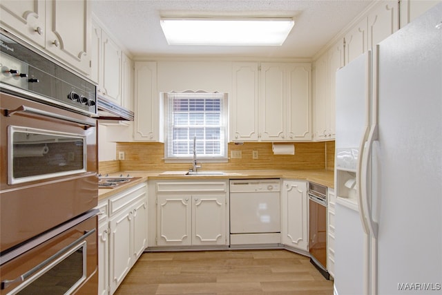 kitchen featuring sink, stainless steel appliances, decorative backsplash, white cabinets, and light wood-type flooring