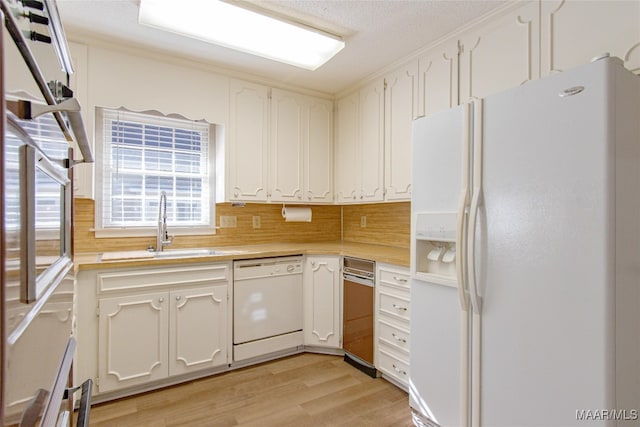 kitchen featuring sink, tasteful backsplash, white appliances, white cabinets, and light wood-type flooring