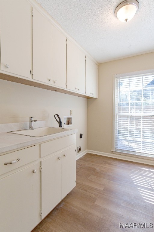 laundry area with cabinets, sink, hookup for a washing machine, hookup for an electric dryer, and light hardwood / wood-style floors