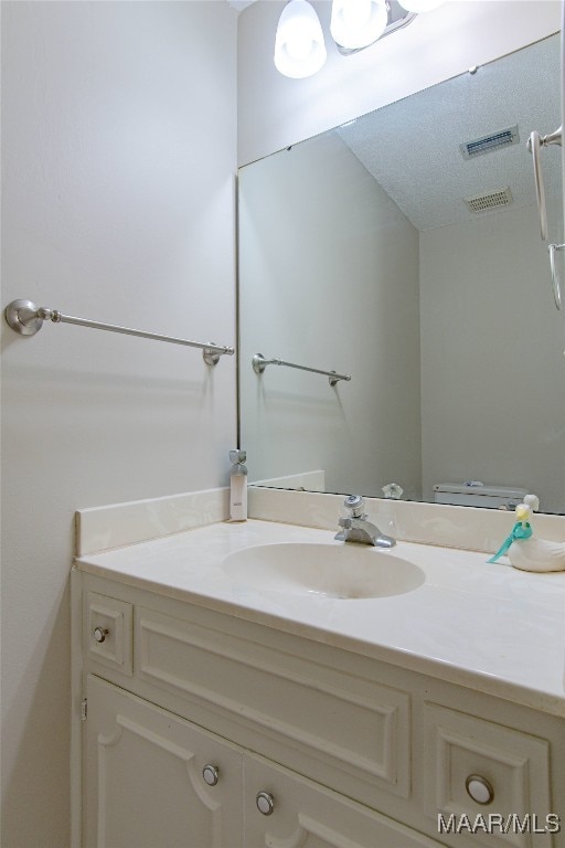 bathroom with vanity, a textured ceiling, and toilet