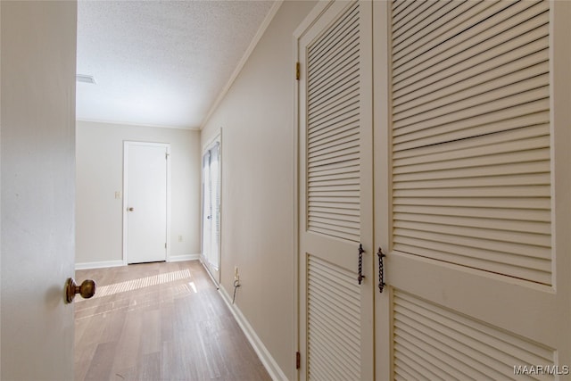 corridor with hardwood / wood-style flooring, ornamental molding, and a textured ceiling