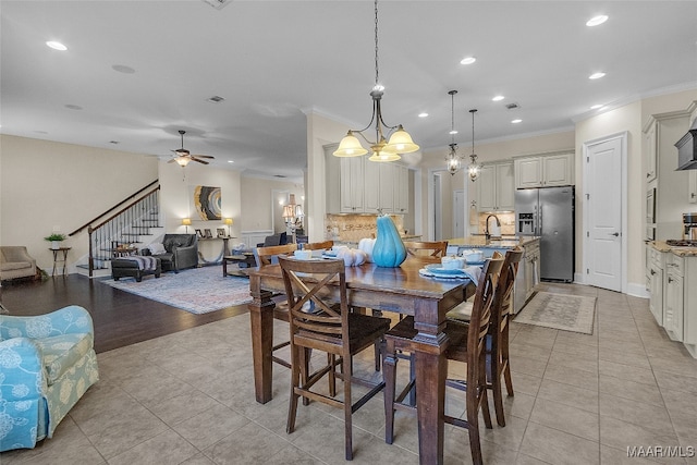 dining area featuring ornamental molding, ceiling fan with notable chandelier, and light hardwood / wood-style flooring