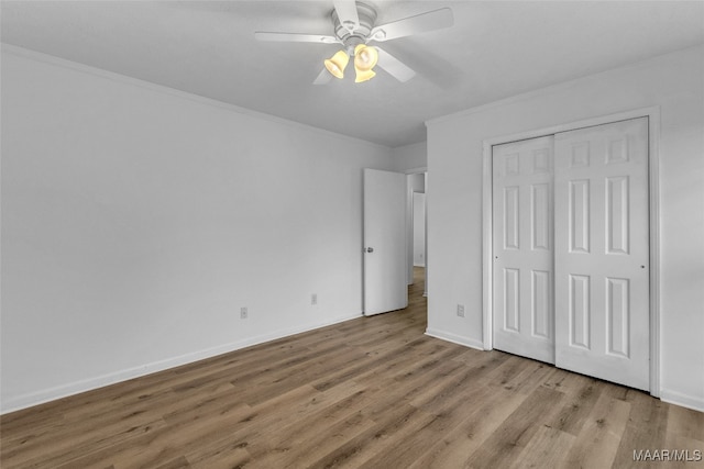 unfurnished bedroom with light hardwood / wood-style flooring, a closet, ceiling fan, and crown molding