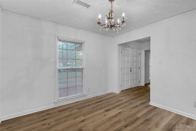 empty room with hardwood / wood-style flooring, a chandelier, ornamental molding, and a textured ceiling