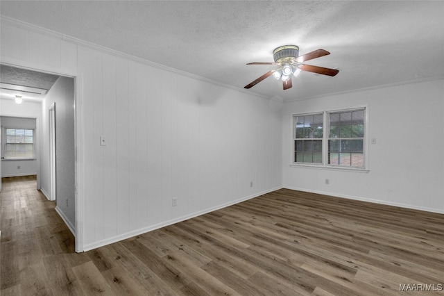 empty room with ornamental molding, wood-type flooring, a textured ceiling, and ceiling fan