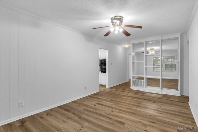 empty room with ornamental molding, wood-type flooring, and ceiling fan