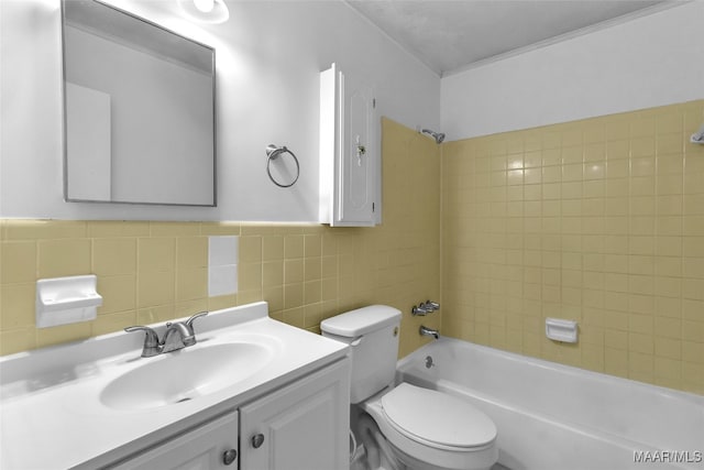 full bathroom with tile walls, vanity, toilet, and tiled shower / bath