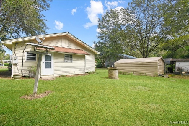 back of house featuring a storage unit, a lawn, and an outbuilding