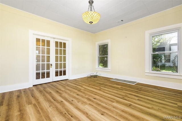 unfurnished room featuring visible vents, wood finished floors, french doors, and a healthy amount of sunlight