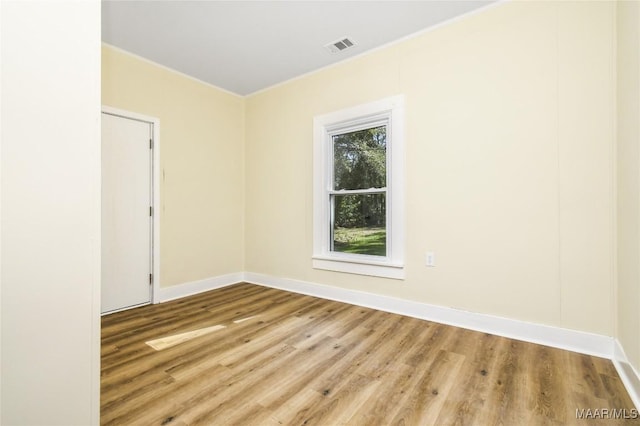 empty room with baseboards, visible vents, and wood finished floors