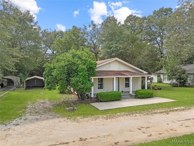 bungalow with a front lawn, a carport, covered porch, and dirt driveway