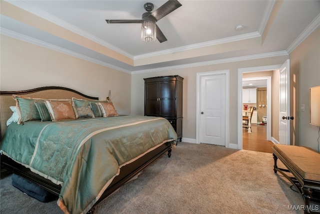 bedroom featuring carpet floors, a tray ceiling, ornamental molding, and ceiling fan