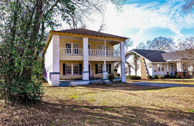 view of front of house with a balcony and a front yard