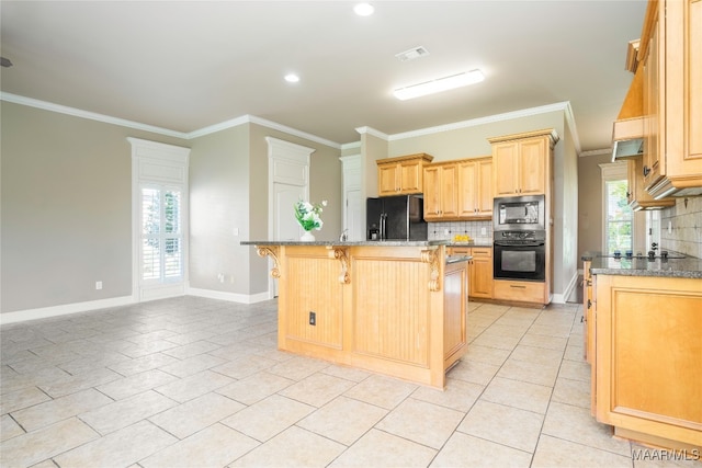 kitchen featuring a kitchen island, light stone countertops, plenty of natural light, and black appliances