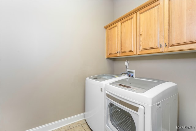 laundry room with washer and clothes dryer, light tile patterned floors, and cabinets