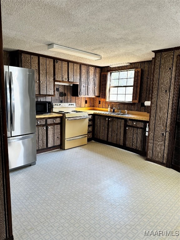 kitchen with dark brown cabinets, white range with electric cooktop, stainless steel refrigerator, and a textured ceiling