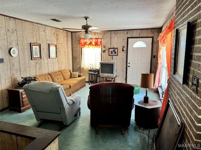 living room with dark carpet, a textured ceiling, wooden walls, and ceiling fan