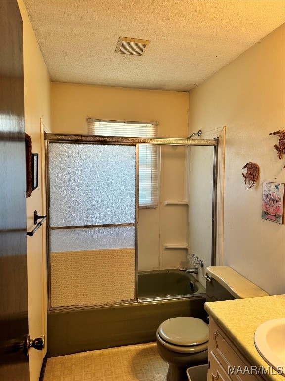 full bathroom featuring a textured ceiling, shower / bath combination with glass door, toilet, and vanity