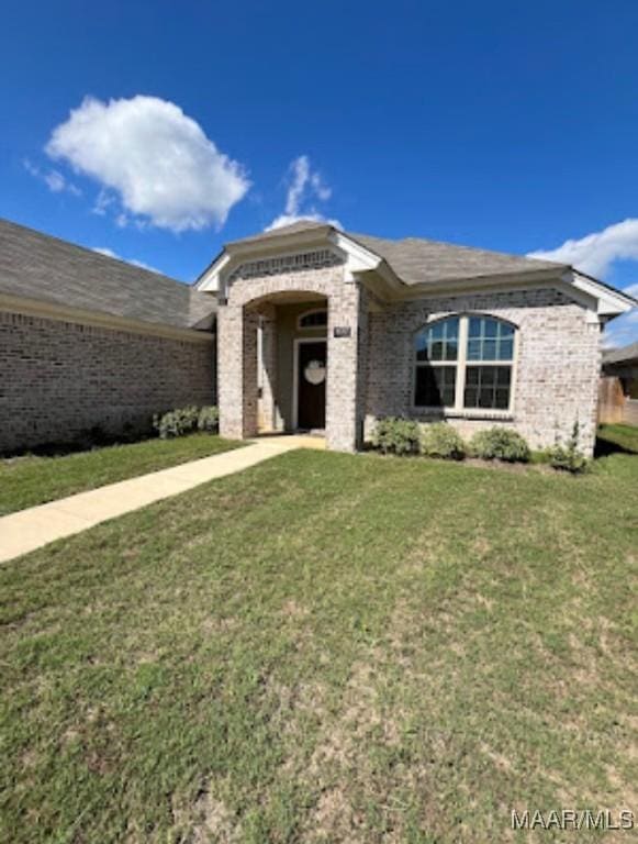 single story home featuring brick siding and a front lawn