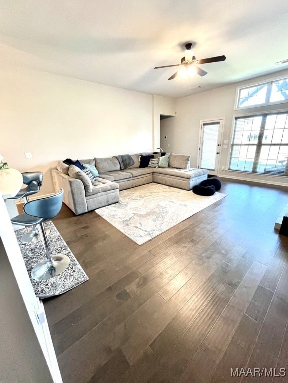 living room with ceiling fan and dark wood-type flooring