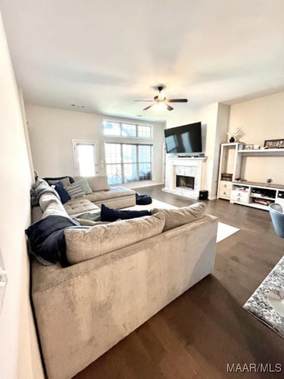 living room with a ceiling fan, a fireplace, and dark wood-style flooring