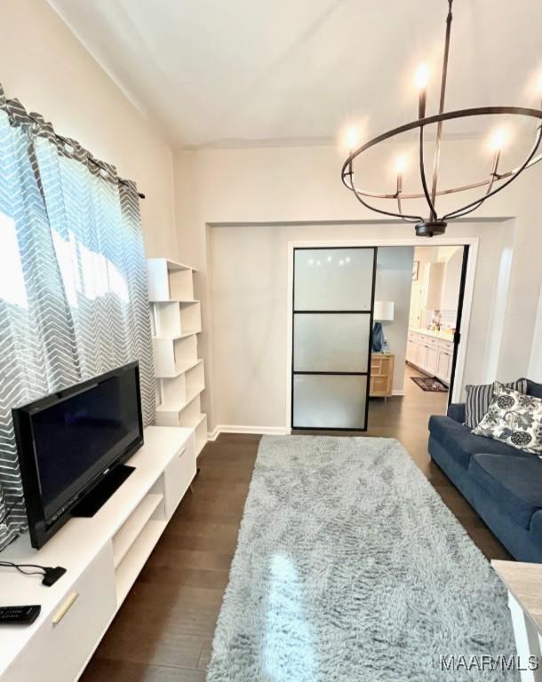 living room featuring a chandelier, dark wood finished floors, and baseboards