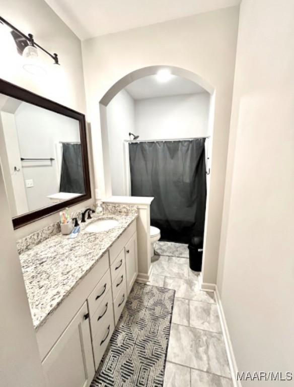 bathroom with vanity, toilet, curtained shower, and baseboards