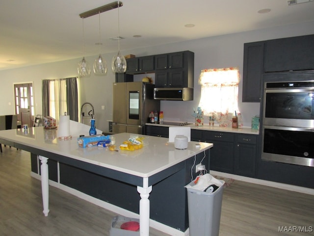 kitchen featuring a healthy amount of sunlight, appliances with stainless steel finishes, and a kitchen island with sink